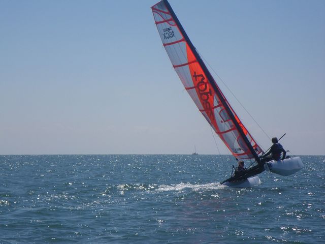 A catamaran sailing on one hull at sea